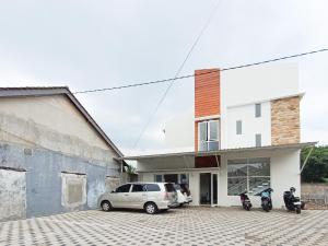 Happy Family Homestay Jember Mitra RedDoorz في جيمبر: اثنين من الدراجات النارية متوقفة في موقف للسيارات أمام منزل
