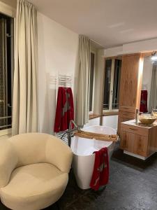 a bathroom with a tub and a chair and a couch at Penthouse Traum - Blick über Arnstadt in Arnstadt