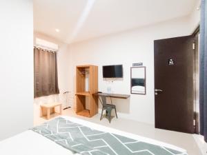 Happy Family Homestay Jember Mitra RedDoorz في جيمبر: غرفة بها مكتب وتلفزيون على الحائط