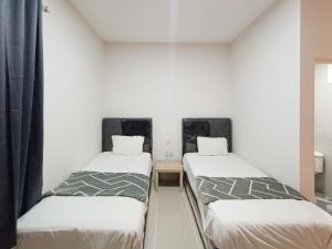 Happy Family Homestay Jember Mitra RedDoorz في جيمبر: سريرين في غرفة بجدران بيضاء