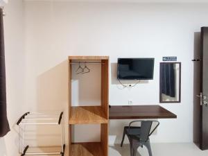 Happy Family Homestay Jember Mitra RedDoorz في جيمبر: غرفة صغيرة مع مكتب وتلفزيون