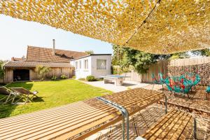 a backyard with a wooden bench and chairs and a table at la Villa du Thar - plage 300m piscine babyfoot arcade pingpong pétanque in Saint-Pair-sur-Mer