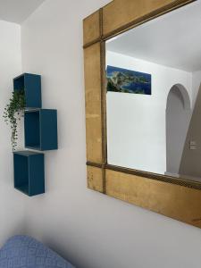 a mirror hanging on a wall with a blue shelf at Plage St-Anne T2 balcon in Sainte-Anne