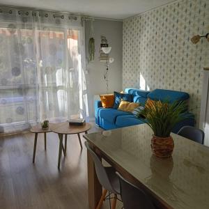 Una sala de estar con un sofá azul y una mesa. en Appartement T2, en Argelès-Gazost