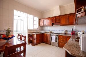 a kitchen with wooden cabinets and a table with a bowl of fruit at Levada House Prazeres in Prazeres
