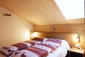 a bed in a room with a wooden ceiling at SKYWAY LOFT - Residence Veronza con piscina, Dolomiti Affitti in Cavalese