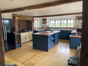 eine große Küche mit blauen Schränken und Holzböden in der Unterkunft Old Cottage - English Countryside Retreat in Lindsell