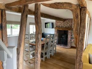 ein Wohnzimmer mit Tisch und Stühlen und einem Kamin in der Unterkunft Old Cottage - English Countryside Retreat in Lindsell