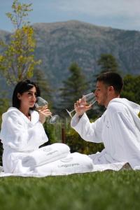a man and woman sitting on the grass drinking wine at Glamping & Spa Luna Azzurra in Sulmona