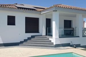 a white house with stairs and a swimming pool at Casa con piscina privada y garaje cerca de Sevilla in Alcalá de Guadaira