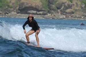a man riding a wave on a surfboard in the ocean at Tata Surf Hostel in Kuta Lombok