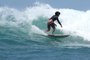 a man riding a wave on a surfboard in the ocean at Tata Surf Hostel in Kuta Lombok