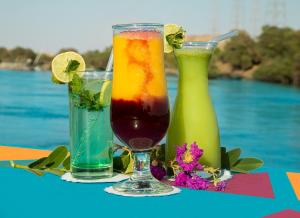 two cocktails sitting on a table next to a pool at Dolty Kato Nubian House By Kato Dool in Aswan