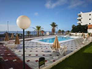 a swimming pool with lawn chairs and umbrellas at Apartamento Tobago in Puerto Rico de Gran Canaria
