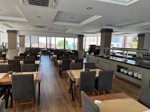 a dining room with tables and chairs and windows at SiDE GOLDEN ROCK HOTEL&SPA in Side