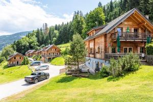 a log house with a car parked in a parking lot at Hüttendorf Schladming in Schladming