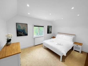 a white bedroom with a white bed and a window at Mallards - English Countryside Retreat in Lindsell