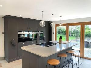 a kitchen with a large island with bar stools at Mallards - English Countryside Retreat in Lindsell