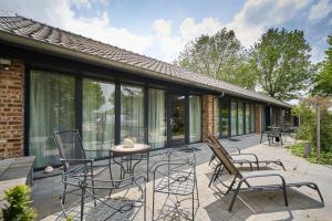 a patio with chairs and a table and some windows at Meschermolen in Mesch