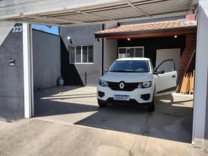 a white car parked in front of a garage at Casa de Praia Golfinhos in Caraguatatuba
