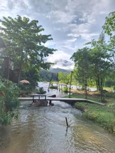 a bridge over a river with a swing at โดมอิงธาร บ้านสวนสราญชล in Ban Plai Nam (2)