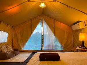a bedroom with a tent with a large window at โดมอิงธาร บ้านสวนสราญชล in Ban Plai Nam (2)