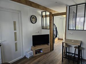 a living room with a flat screen tv and a table at Petit Appart proche IMA in Niort