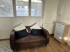 a brown leather couch with two pillows on it at Petit Appart proche IMA in Niort