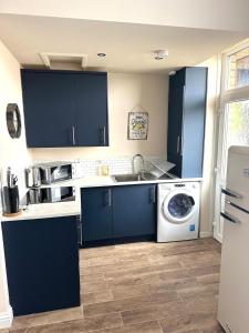 a kitchen with blue cabinets and a washing machine at Prestwick KingB PetsOk FreeP Wifi Tv in Prestwick