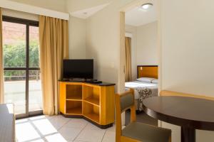 a hotel room with a television and a table and a bed at Golden Suíte Hotel in Campinas