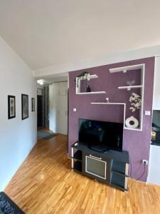 a living room with a tv and a purple wall at City view & pool apartment 2 in Niš