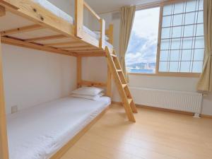 a bedroom with two bunk beds and a window at Otaru Garden Stay in Otaru