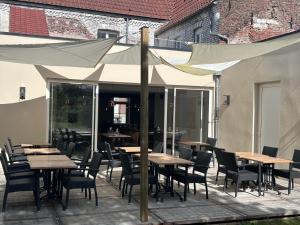 a patio with wooden tables and chairs and umbrellas at Le Bonhomique in Seclin