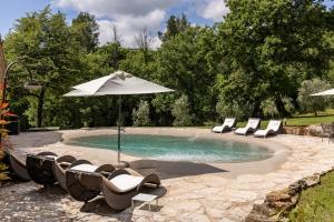 a swimming pool with lounge chairs and an umbrella at Borgo Pietraio Casa Vacanze in Radicondoli