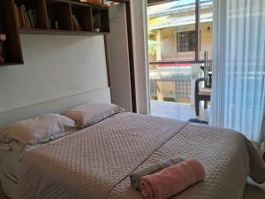 Un dormitorio con una cama con dos almohadas y una ventana. en Suíte Pé na Areia do Flamengo, en Salvador