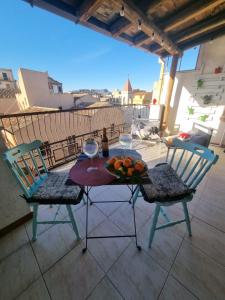 a table with two chairs and wine glasses on a balcony at La Gorgone city center apartments in Casteldaccia