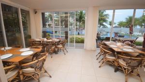 un restaurant avec des tables et des chaises en bois et des fenêtres dans l'établissement Paraíso à beira-mar: Beach Living by FTT, à Mangabeira