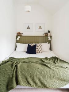 a bedroom with a bed with a green blanket and pillows at Sweet Pea Cottage in Tideswell