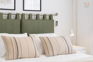 a bed with white pillows and a green headboard at Linda House in Maspalomas +13 photos