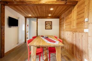a dining room with a wooden table and red chairs at Appartamento Pila Vacanze in Gressan