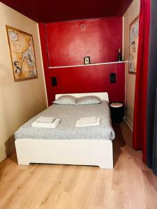 a bedroom with a white bed with a red wall at Maison Intramuros 3 chambres 3 salles de bain - Idéal Festival in Avignon