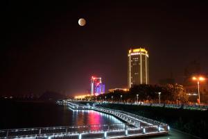 a view of a city at night with the moon at Crowne Plaza Zhenjiang by IHG in Zhenjiang