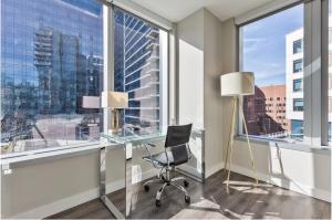 an office with a glass desk and a chair in front of a window at Modern Apt in Seaport with Gym in Boston