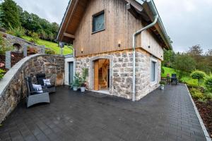 a stone house with a patio and a stone wall at Waldlux Luxus-Chalet Brennhus in Kappelrodeck