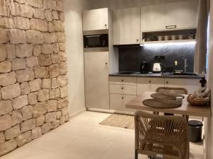 a kitchen with a table and a stone wall at Almyra Boutique Suites with Private Pool -Finiki in Foinikion