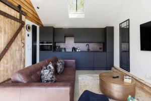 a living room with a brown couch and a kitchen at Romantic Countryside Lodge with Hot Tub in North Mundham