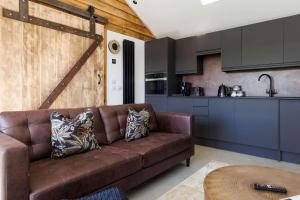 a living room with a brown couch in a kitchen at Romantic Countryside Lodge with Hot Tub in North Mundham