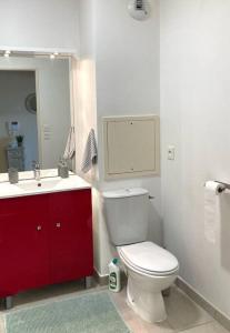 a bathroom with a white toilet and a red cabinet at Chez karine 4 in Arpajon +8 photos