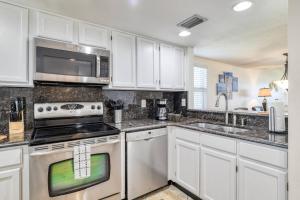a kitchen with white cabinets and stainless steel appliances at Pier Point 57 in St. Augustine +42 photos