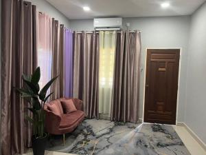 a living room with a chair and some curtains at Dflora Roomstay in Kampong Guntong